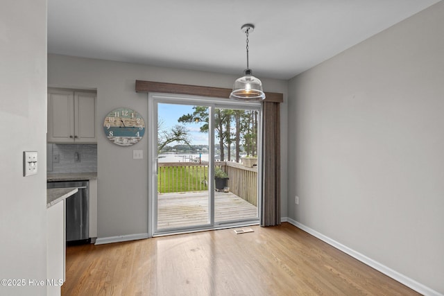 unfurnished dining area featuring baseboards, visible vents, and light wood-style floors