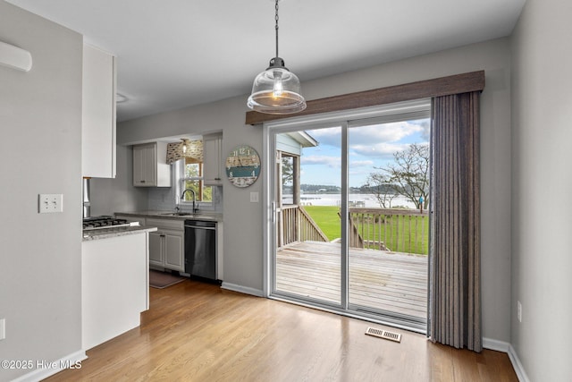 kitchen with pendant lighting, light wood finished floors, visible vents, and dishwasher