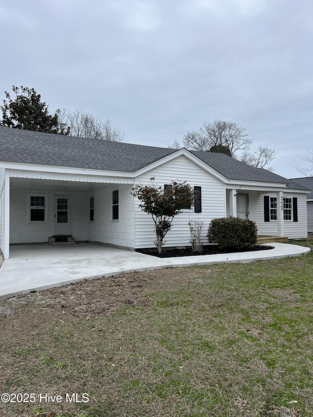 exterior space featuring an attached carport, a front yard, and a shingled roof