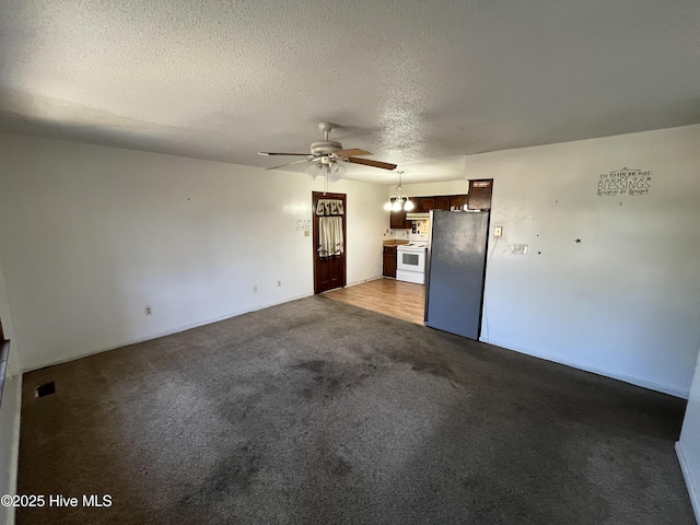 unfurnished living room featuring ceiling fan, a textured ceiling, and dark carpet