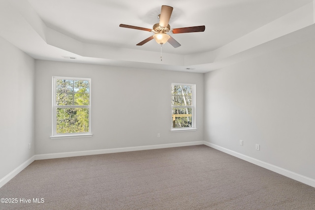 spare room with baseboards, a tray ceiling, and carpet flooring