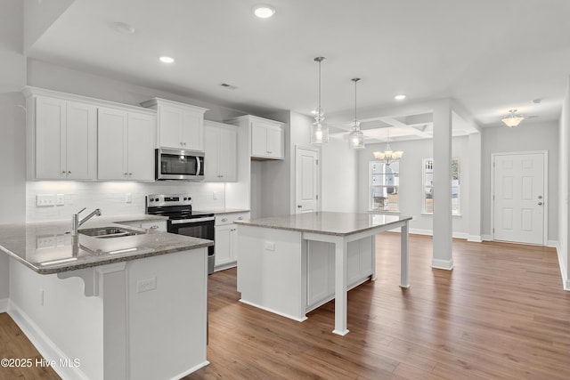 kitchen featuring stainless steel appliances, a sink, white cabinetry, a kitchen breakfast bar, and backsplash