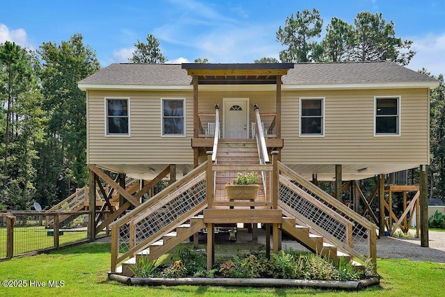 view of front facade with a shingled roof, a front yard, and stairway