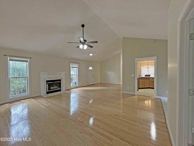 unfurnished living room with ceiling fan, lofted ceiling, a fireplace, and light hardwood / wood-style flooring