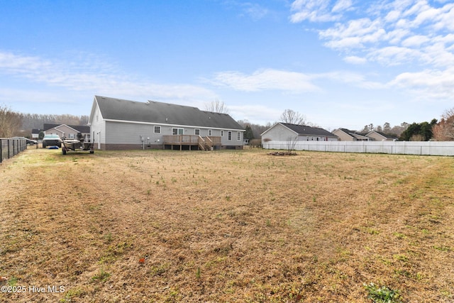 back of property featuring a lawn, a deck, and fence