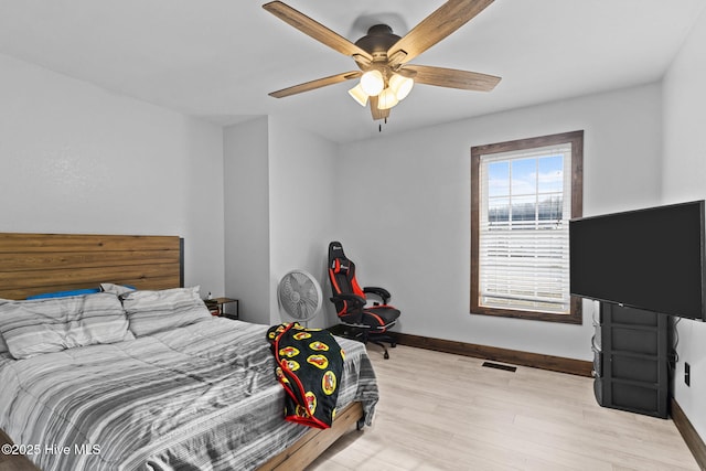 bedroom with light wood finished floors, visible vents, a ceiling fan, and baseboards