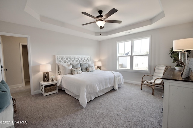 bedroom featuring a raised ceiling, carpet flooring, and ceiling fan