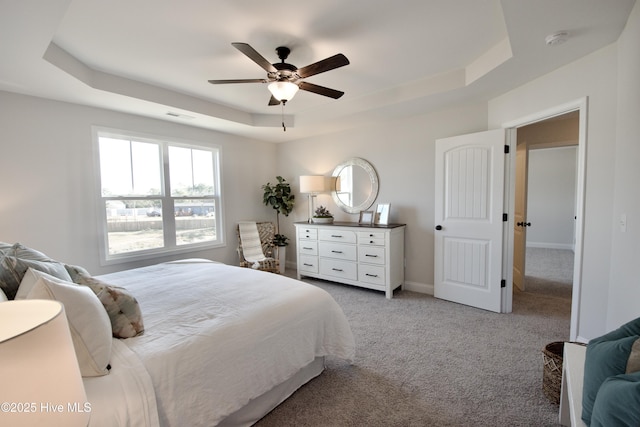 bedroom featuring ceiling fan, light colored carpet, and a tray ceiling