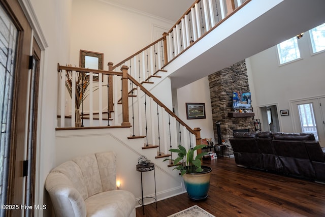 foyer with stairs, a fireplace, a high ceiling, and wood finished floors