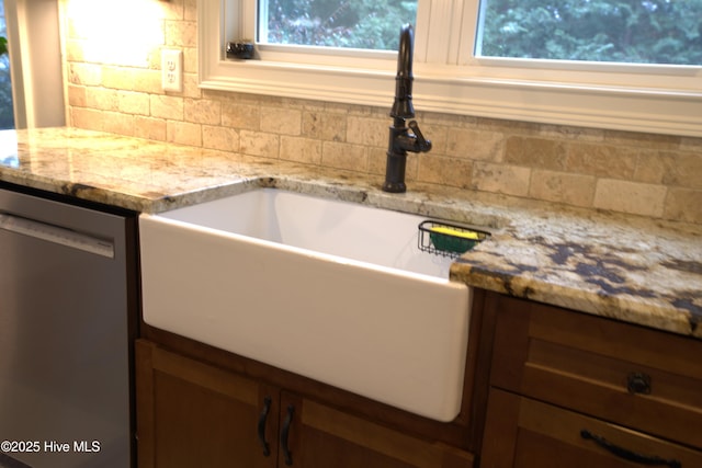 kitchen featuring dishwasher, light stone counters, plenty of natural light, and a sink