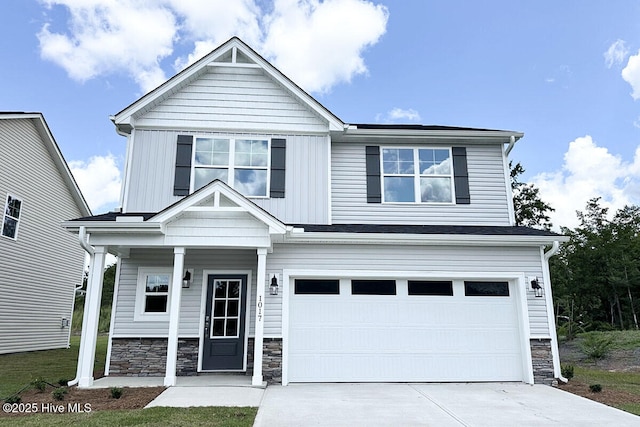 craftsman-style home with an attached garage, board and batten siding, concrete driveway, and stone siding