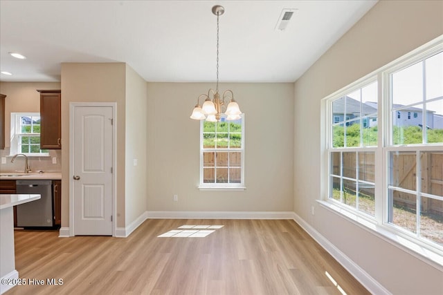 unfurnished dining area featuring a chandelier, a sink, baseboards, and visible vents
