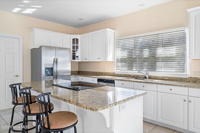 kitchen featuring appliances with stainless steel finishes, a kitchen island, white cabinets, and a breakfast bar area