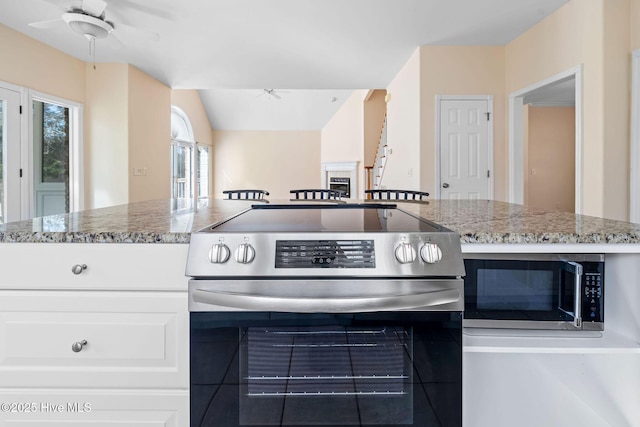 kitchen with white cabinetry, appliances with stainless steel finishes, light stone countertops, and ceiling fan