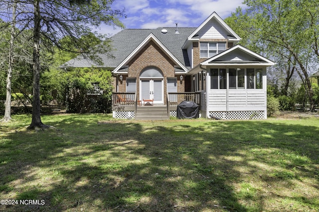 view of front of property featuring a sunroom, a wooden deck, and a front lawn