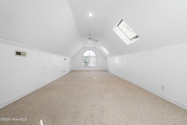 bonus room with vaulted ceiling with skylight, ceiling fan, and light colored carpet