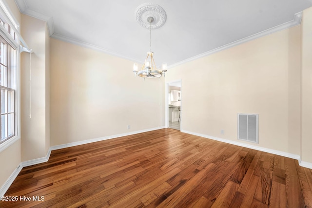 empty room featuring hardwood / wood-style flooring, crown molding, and a wealth of natural light