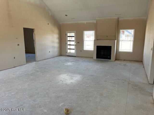 101 Mill Creek Rd, Edenton, NC 27932 - unfurnished living room featuring unfinished concrete floors, a fireplace, and a towering ceiling