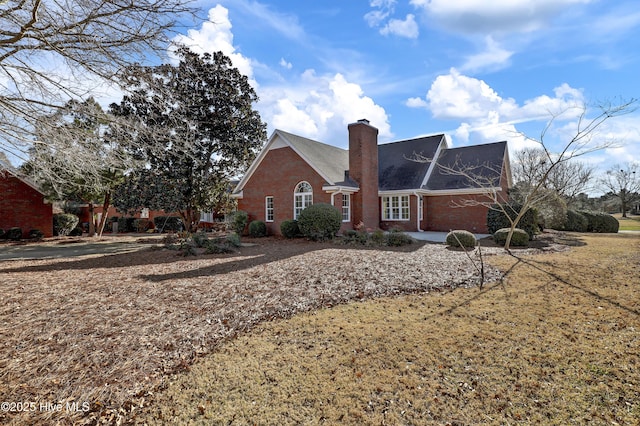 exterior space featuring a yard, a chimney, and brick siding