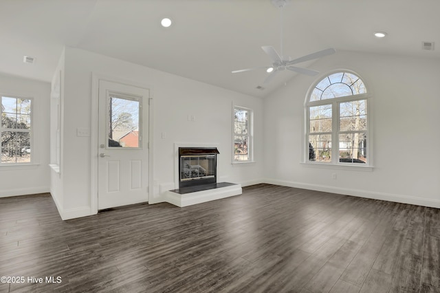 unfurnished living room with dark wood-style flooring, a glass covered fireplace, and a wealth of natural light