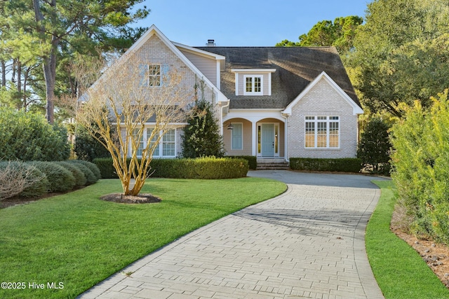 traditional-style home with brick siding, decorative driveway, and a front yard