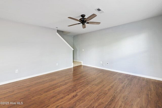 6507 Rustling Leaves Way, Wilmington, NC 28409 - spare room featuring a ceiling fan, baseboards, dark wood-style flooring, and stairs