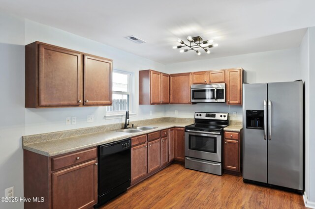 6507 Rustling Leaves Way, Wilmington, NC 28409 - kitchen featuring appliances with stainless steel finishes, a sink, wood finished floors, light countertops, and a chandelier