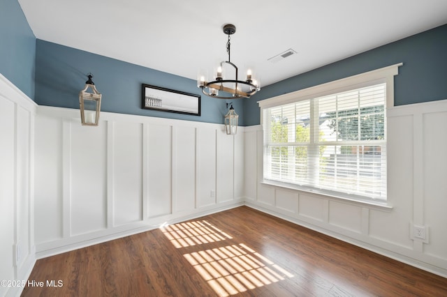 unfurnished dining area featuring an inviting chandelier and wood-type flooring