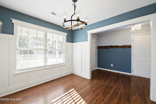 6507 Rustling Leaves Way, Wilmington, NC 28409 - unfurnished dining area featuring a chandelier, a decorative wall, a wainscoted wall, and wood finished floors