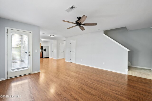 6507 Rustling Leaves Way, Wilmington, NC 28409 - unfurnished living room with a ceiling fan, stairs, light wood finished floors, and baseboards