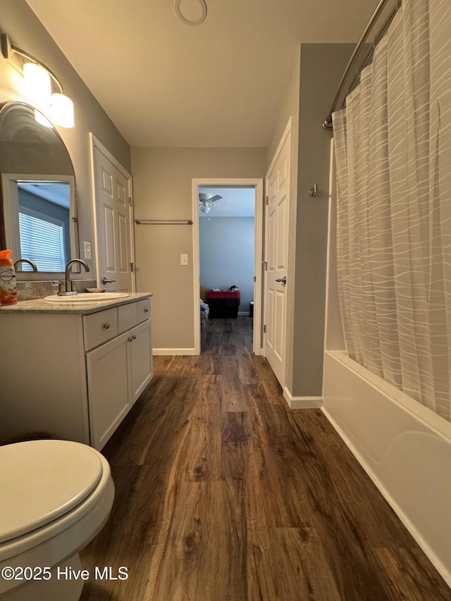 full bath featuring shower / tub combo, vanity, baseboards, and wood finished floors