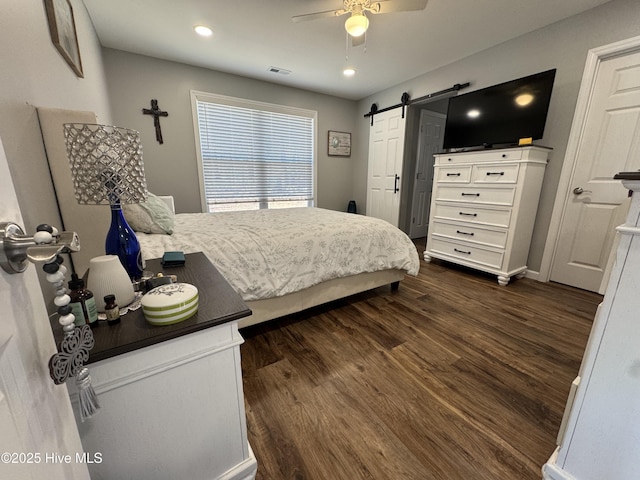 bedroom with dark wood finished floors, recessed lighting, visible vents, a barn door, and a ceiling fan