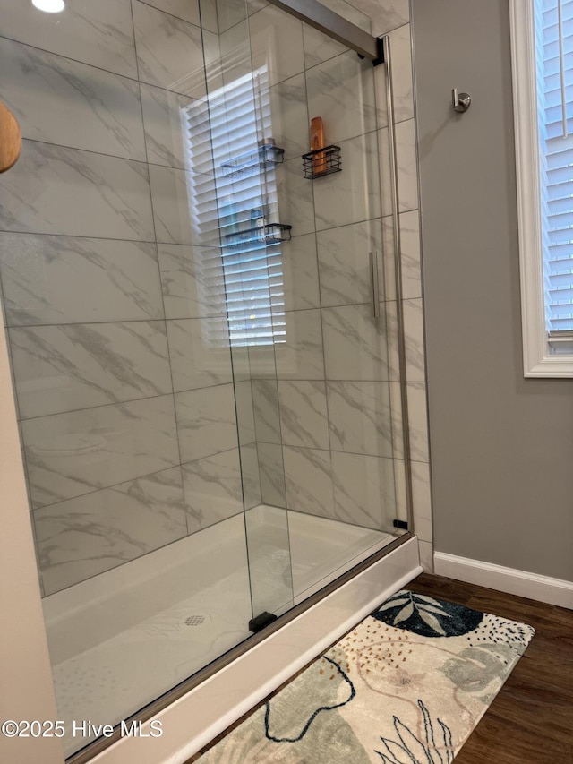 bathroom with a stall shower, baseboards, and wood finished floors