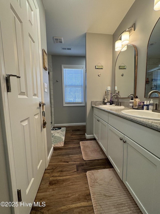 full bath with visible vents, a tile shower, a sink, and wood finished floors