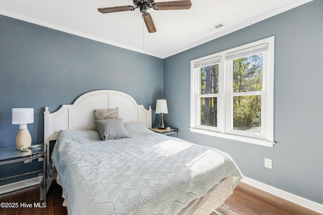 bedroom with visible vents, ornamental molding, ceiling fan, wood finished floors, and baseboards