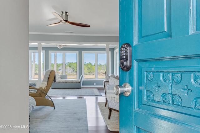 interior space featuring wood finished floors, crown molding, a ceiling fan, and visible vents