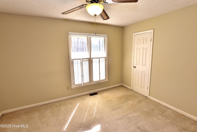 carpeted empty room with ceiling fan, baseboards, and plenty of natural light