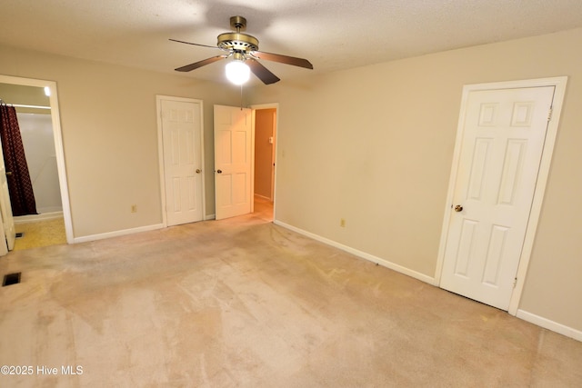 unfurnished bedroom with light carpet, baseboards, two closets, and visible vents