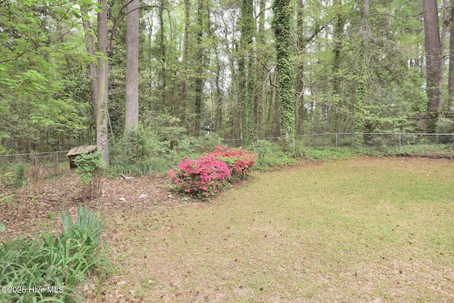 view of yard with a wooded view and fence