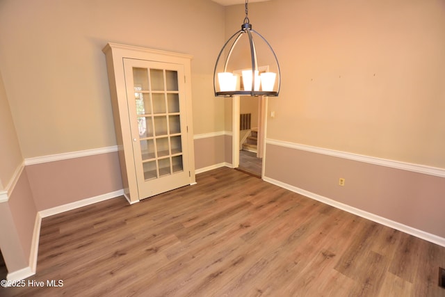 unfurnished dining area featuring wood finished floors, baseboards, visible vents, and stairway