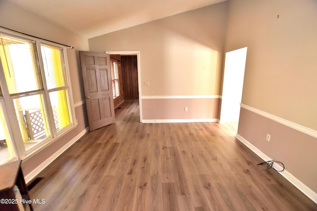 unfurnished room featuring visible vents, light wood-type flooring, baseboards, and lofted ceiling