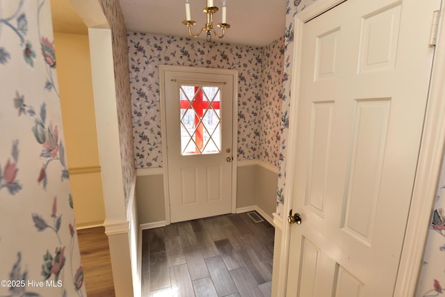 foyer featuring wallpapered walls, an inviting chandelier, and wood finished floors
