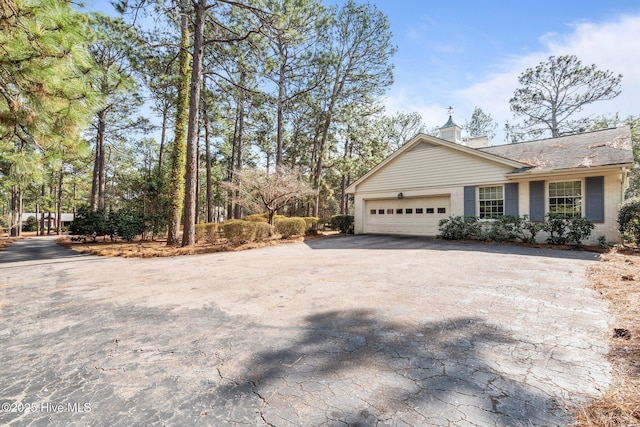 view of side of property with aphalt driveway, an attached garage, and brick siding