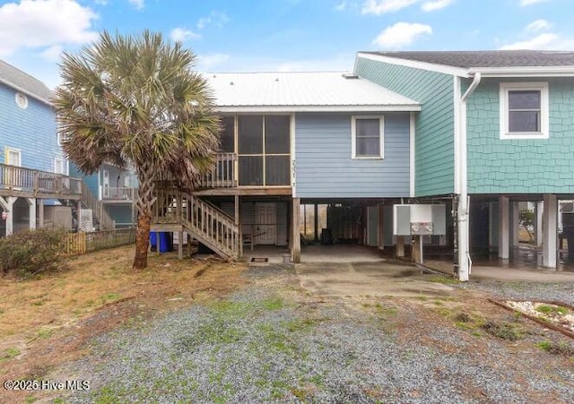 rear view of property with a sunroom and a carport