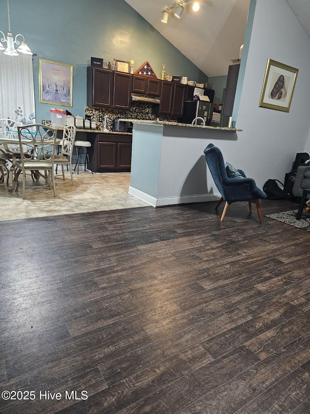 kitchen featuring pendant lighting, a kitchen bar, hardwood / wood-style flooring, dark brown cabinetry, and kitchen peninsula