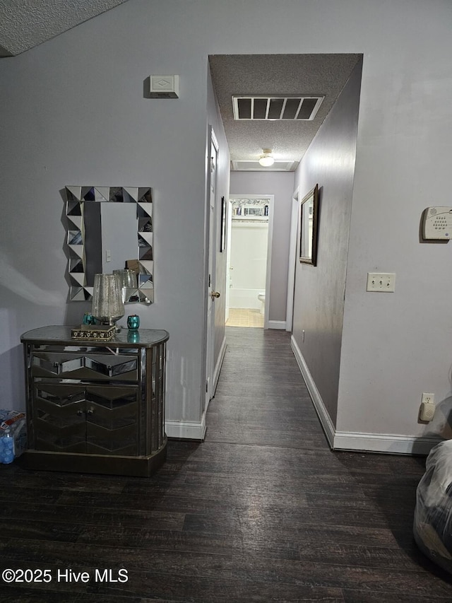 hallway with dark wood-type flooring and a textured ceiling