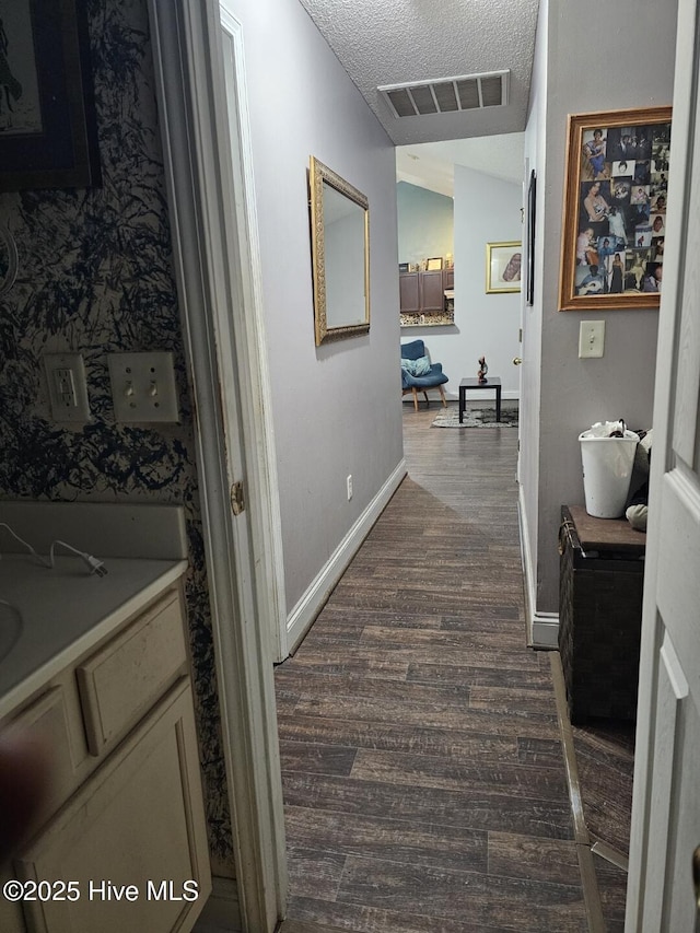 hall with dark hardwood / wood-style flooring, vaulted ceiling, and a textured ceiling