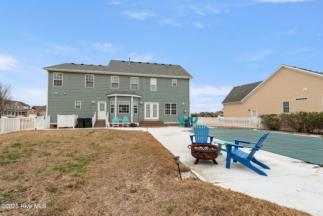 back of property with a yard, a patio, entry steps, a fenced backyard, and a fire pit