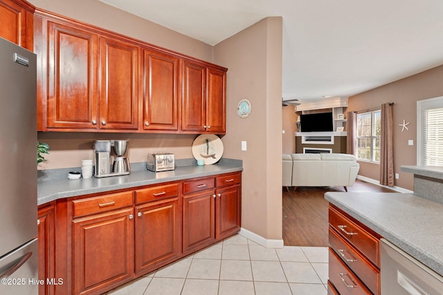 kitchen featuring freestanding refrigerator, open floor plan, light tile patterned flooring, and baseboards