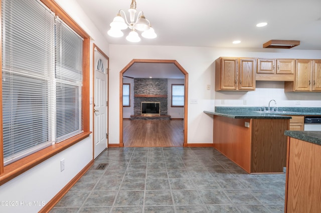 kitchen with dark tile patterned floors, a fireplace, baseboards, dark countertops, and pendant lighting